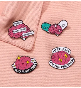 Détail de quatre épingles en émail rose sur le thème du cerveau sur un tissu rose texturé