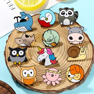 Detailed close-up of colorful enamel animal brooches on a rustic wooden plate