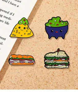 Close-up of four food enamel pins including taco and sandwich on a cork background