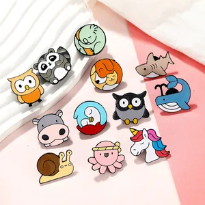 Close-up of cute cartoon enamel animal pins including owl snail and whale designs