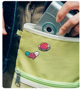 Broches en émail sur la santé mentale avec cerveau et capsule sur un sac bandoulière vert