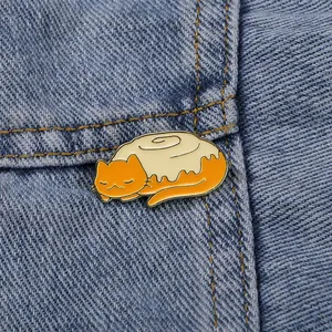 Cute orange cat enamel pin combined with a cinnamon roll design on blue denim fabric