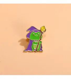 Dettaglio di una spilla smaltata a forma di rana mago con cappello viola e scettro