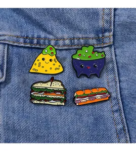 Detailed view of four food enamel pins pinned onto a blue denim jacket fabric