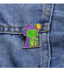 Primo piano di una spilla smaltata rana mago con cappello viola su tessuto denim