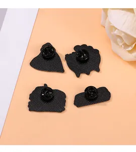 Detail of four black enamel brooch backs with anti-slip grid texture and clutch pins