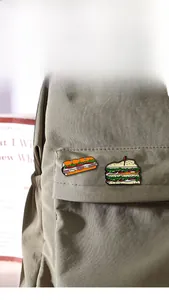 Detail of food enamel pins showing a burger and sandwich on a khaki canvas backpack