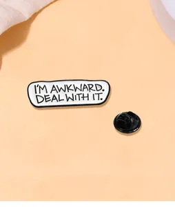 Detail von Emaille-Anstecker mit Text I'M AWKWARD DEAL WITH IT auf orangefarbenem Grund