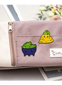 Detail of cute enamel pins with corn chips and avocado dip on canvas pencil case