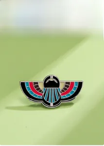 Close-up of Egyptian winged scarab enamel brooch with colorful inlay and gold metal lines