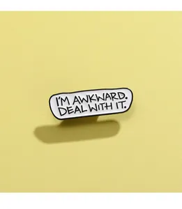Detail der Emaille-Anstecknadel mit Text I'M AWKWARD DEAL WITH IT auf gelbem Grund