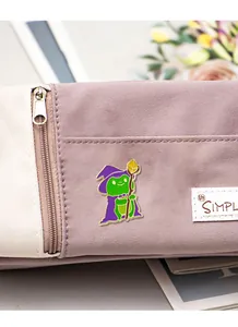 Dettaglio di una spilla in smalto con rana mago fissata su una borsa di tela viola