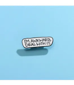 Makroaufnahme der Emaille-Brosche mit Text I'M AWKWARD. DEAL WITH IT auf blauem Grund