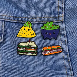 Set of four cartoon food enamel pins including taco and sandwich on blue denim fabric