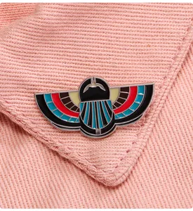 Macro detail of Egyptian Scarab enamel brooch with colorful inlay on a fabric collar