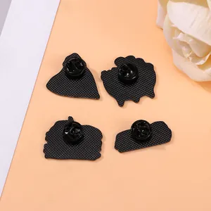 Back view of four black metal burger brooches with secure rubber pin clutch backings
