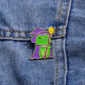Spilla smaltata con mago rana, mantello viola e bastone su tessuto denim blu