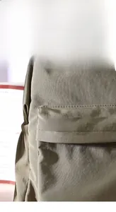 Detail der Emaille-Anstecknadel mit Spruch auf grünem Canvas-Rucksack befestigt