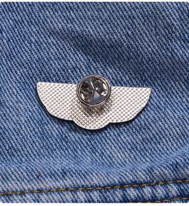 Macro shot of silver wing brooch back with butterfly clutch on denim fabric