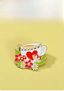Vue détaillée d'un pin's en émail en forme de tasse à thé avec cœur champignon et fleurs