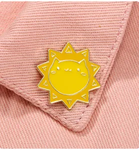 Gros plan d'une broche émaillée soleil avec chat mignon sur un col rose en tissu