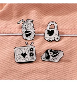 Detail of four creative black and white enamel pins with heart motifs on denim fabric