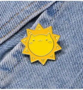 Détail d'un badge émaillé jaune chat soleil fixé sur un tissu en denim bleu