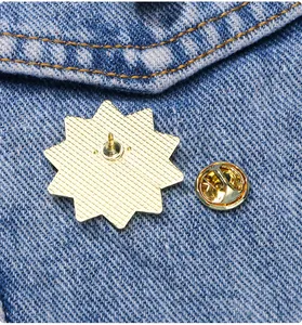 Détail de l'arrière d'une broche soleil dorée avec fermoir papillon sur tissu bleu