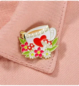 Vue macro d'une broche tasse en émail épinglée sur une veste en tissu rose texturé