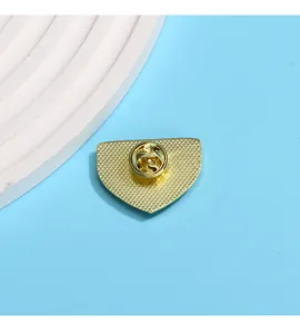 Détail du fermoir papillon en métal et texture quadrillée dorée au dos du badge