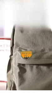 Détail d'un pin's émaillé d'aventure avec motif de montagne sur un sac à dos en toile verte