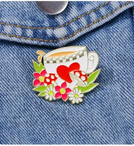 Détail d'une broche en émail avec tasse de thé et champignons sur veste en denim