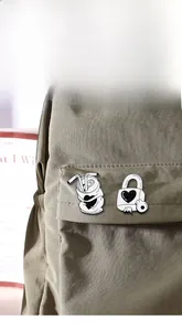 Detail of vintage heart soda can and lock enamel pins on a khaki canvas bag