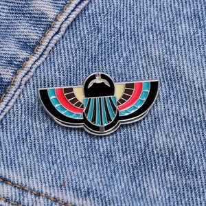 Egyptian style winged scarab enamel brooch pin on denim fabric for casual outfits