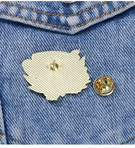 Détail du dos de la broche dorée avec texture quadrillée et fermoir papillon sécurisé