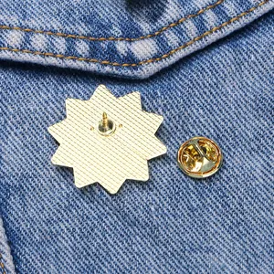 Broche soleil japonaise avec plaque étoile dorée et fermoir papillon sur denim