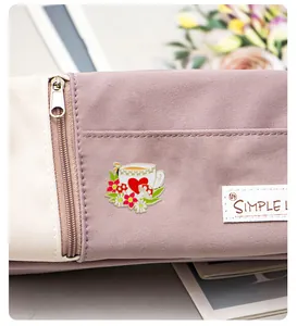 Détail d'une broche en émail avec tasse de thé et champignon sur un sac en toile violet