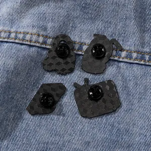Set of four retro enamel pins on blue denim fabric showing back side with texture
