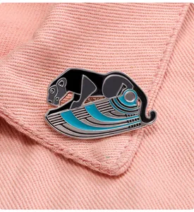 Detail of a geometric black and blue enamel leopard brooch on pink fabric background