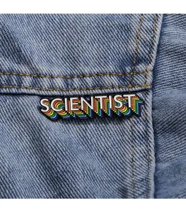 Makroaufnahme der bunten SCENTIST Emaille-Anstecknadel mit Regenbogen auf Denim-Stoff
