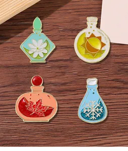 Detailed view of four enamel pins featuring four seasons motifs on dark wood backdrop