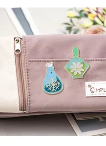Detail of cute enamel pins with snowflake and flower designs on a purple canvas bag