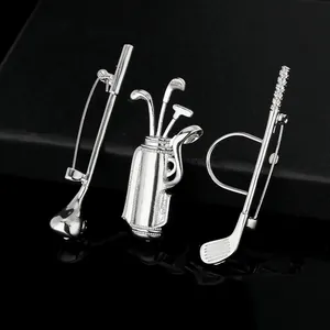 Macro shot of silver golf club and bag brooch set with rhinestones on black reflective base