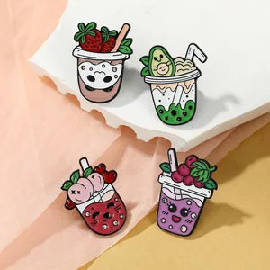 Nahaufnahme bunter Emaille-Pins mit Fruchtmilchtee-Motiven auf Dekorhintergrund