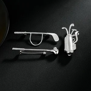 Detailed view of silver golf club and bag brooches set on a black textured background