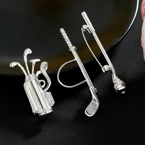 Detailed silver golf club and bag brooches set with polished finish on black background