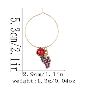 Detail view of gold hoop earring with red bell and purple grape charm with measurements