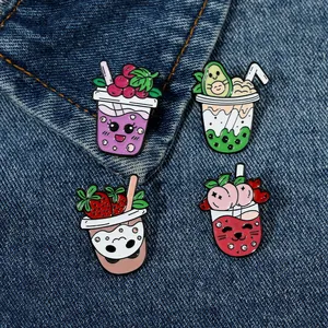 Detail von vier bunten Frucht-Milchtee-Emaille-Pins auf dunkelblauem Denim