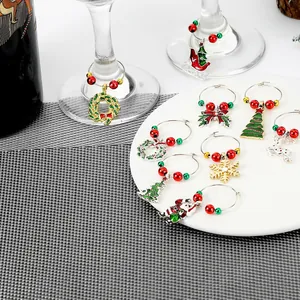 Detail of Christmas wine glass charms with festive metal pendants on a white plate