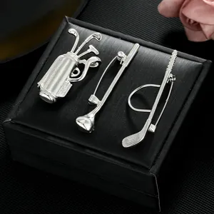 Detailed view of silver golf club and bag brooches on a black textured jewelry box